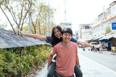 Gülümseyen Asyalı çift strette eğleniyor. Kızı taşıyan adam..
