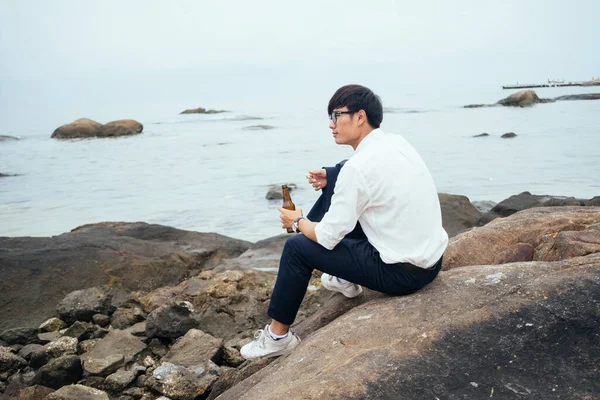 海の岩の上に座って水の上に何かを見ているビジネスマン — ストック写真