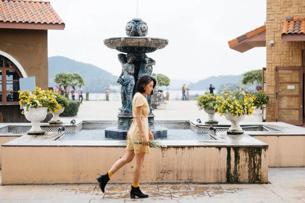 Menina Bonito Andando Com Flores Frente Uma Fonte — Fotografia de Stock