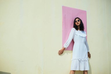 Yazın sarı duvara pembe kağıtla yaslanmış bir kız..