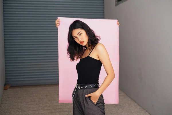 Pembe kağıdın önünde duran havalı elbiseli kısa saçlı kız..