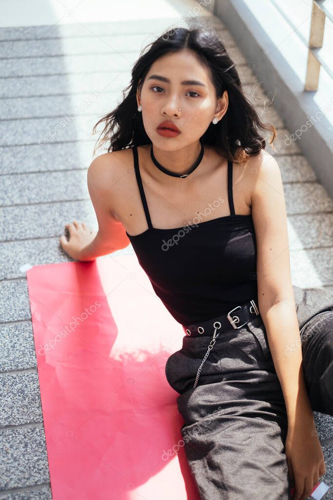 Cool girl sitting at the red paper on a floor.