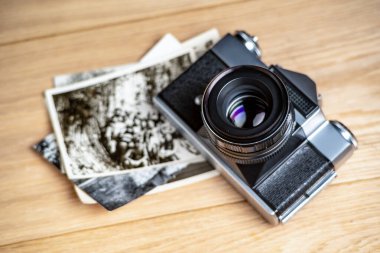 Eski bir retro kamera ve ahşap bir arka planda bazı fotoğraflar. Objektife odaklan. Yakın plan..