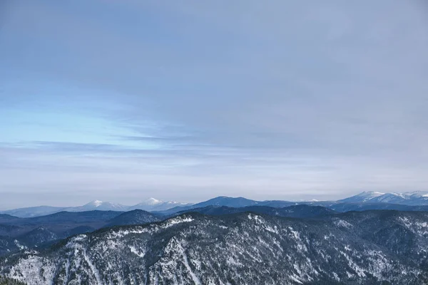 Winter mountain landscape.Snow mountains overgrown with taiga against a blue sky. Top view. Russia. Altai Republic. — Stockfoto