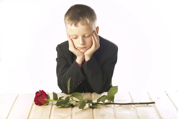 一朵红玫瑰的年轻人。那个男人坐在桌旁. — 图库照片