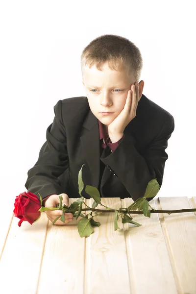 Un joven con una rosa roja. El hombre está sentado a la mesa. . —  Fotos de Stock
