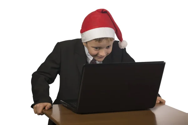 Niño en un sombrero de Santa Claus en la computadora . —  Fotos de Stock