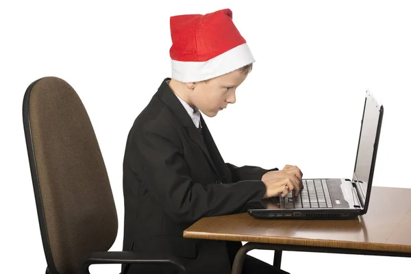 Niño en un sombrero de Santa Claus en la computadora . —  Fotos de Stock