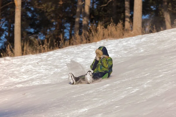 Cara em roupas de inverno está montando em um deslizamento de neve . — Fotografia de Stock