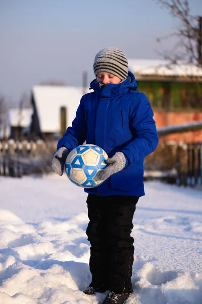 Schuljunge kickt den Ball beim Winterfußball auf dem Sportplatz — Stockfoto