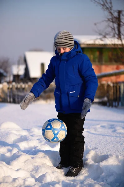 Schuljunge kickt den Ball beim Winterfußball auf dem Sportplatz — Stockfoto