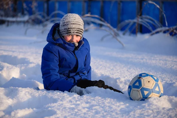 Школьник пинает мяч, играя в зимний футбол — стоковое фото