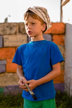 Bir çocuk kapıyı açık hava yaz aylarında açık havada boyama tarafından bir resim yapar. Düzeni tekrar kurmak ve binanın görünümünü iyileştirmek. Fırça boya kavanoza dips.