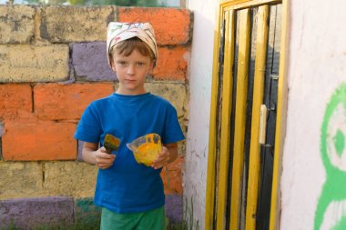 Bir çocuk kapıyı açık hava yaz aylarında açık havada boyama tarafından bir resim yapar. Düzeni tekrar kurmak ve binanın görünümünü iyileştirmek. Fırça boya kavanoza dips.