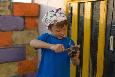 Bir çocuk kapıyı açık hava yaz aylarında açık havada boyama tarafından bir resim yapar. Düzeni tekrar kurmak ve binanın görünümünü iyileştirmek. Fırça boya kavanoza dips.