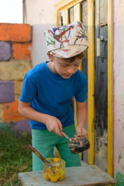 Bir çocuk kapıyı açık hava yaz aylarında açık havada boyama tarafından bir resim yapar. Düzeni tekrar kurmak ve binanın görünümünü iyileştirmek. Fırça boya kavanoza dips.
