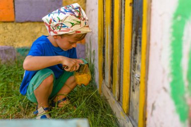 Bir çocuk kapıyı açık hava yaz aylarında açık havada boyama tarafından bir resim yapar. Düzeni tekrar kurmak ve binanın görünümünü iyileştirmek. Fırça boya kavanoza dips.