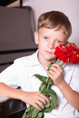 Bir genç piyanist adam bir piyano bir buket çiçek ile oturuyor.