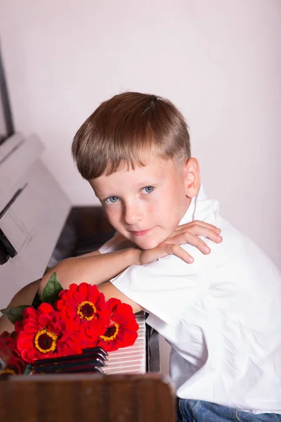 Un giovane pianista siede dietro un pianoforte con un mazzo di fiori — Foto Stock