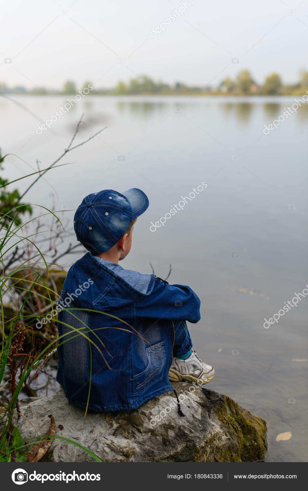 The Boy On The River Bank Travels He Sits On A Large Rock Bould Stock Photo Image By C rbnbvtw