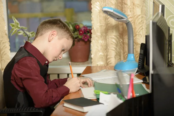 El chico trabaja en su oficina en una computadora personal. Escribe ingenio —  Fotos de Stock