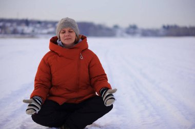 Kadın meditasyon yapıyor. Karla kaplı tarlada oturuyor. Evrenden bir birleşme..