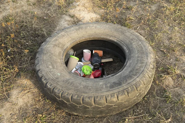 Used plastic bottles lie inside a worn out car tire. Environmental pollution.