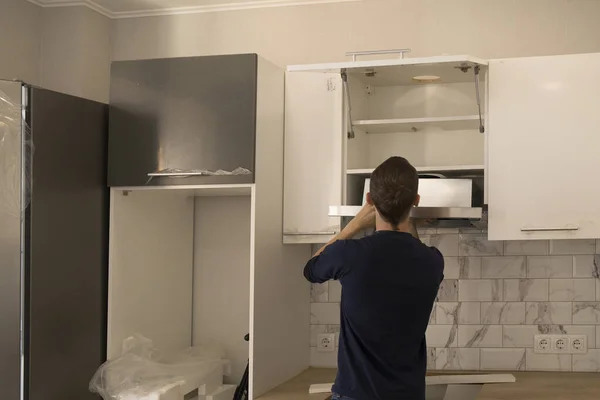 Handyman assemblying home range hood in kitchen furniture