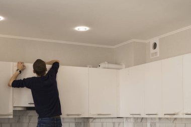 Mutfak mobilyalarında fırın kaputu ve havalandırma birleştiren işçiler