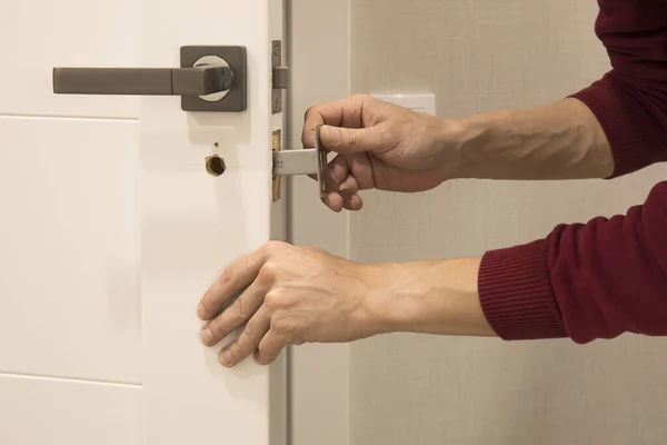 Człowiek naprawiający klamkę. zbliżenie rąk pracowników instalowanie nowej szafki drzwiowej — Zdjęcie stockowe