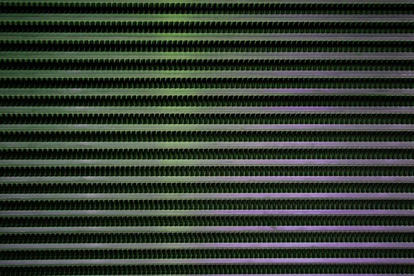 Latticed metal fence surface with jagged stripe elements and green spotlights — 스톡 사진