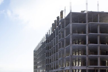 Güneşli bir günde arka planda mavi gökyüzü olan bitmemiş binalı inşaat alanı.