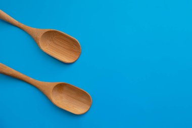 Mavi arka planda ahşap çevre dostu malzeme kaşıkları.