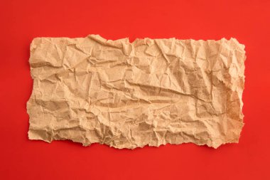Kırmızı zemin üzerinde boş buruşmuş geri dönüştürülmüş kağıt parçası