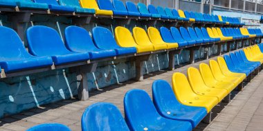 Stadyumdaki ya da oyun alanındaki eski plastik sandalyeler mavi ve sarı. Spor müsabakaları izleyicileri için yerler