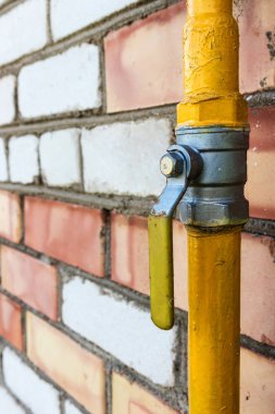 Turnalı sarı gaz borusu eski bir tuğla duvarın ön cephesi boyunca uzanıyor. Ev iç kullanım için benzine bağlı