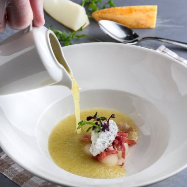 Nane, proshuto ve salatalık ile tureen kavun çorbası dökülen. Beyaz tabak, gri arka planda kaşık. Close