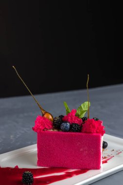 Beyaz, kırmızı parlak dondurma yaban mersini, böğürtlen ve karamel beyaz bir tabakta. Yaratıcı servis yemekleri. Yakın çekim, gri arka plan