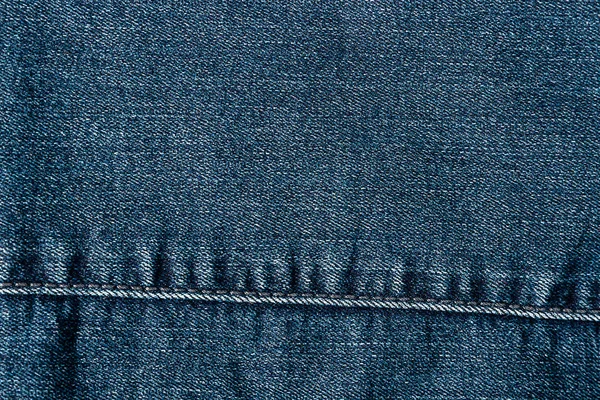 Pohled shora na džínovou texturu se stehem. Plátno džíny pozadí modré barvy s detaily — Stock fotografie