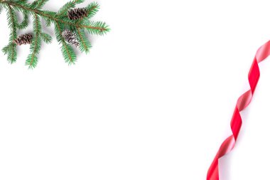 Beyaz arka planda yalıtılmış ladin dalları, koniler ve kırmızı kıvırcık kurdeleli kışın Noel kompozisyonu. Düz konum, üst görünüm, kopyalama alanı