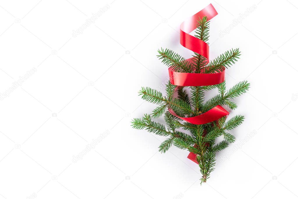 Creative minimalistic winter composition with spruce branch and red curly ribbon that looks like Christmas tree isolated on white background. Flat lay, top view, copy space