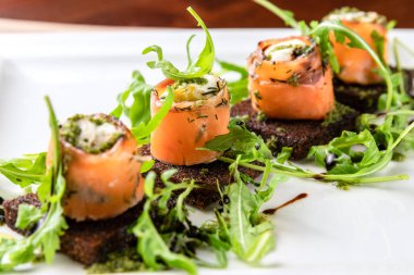 Pastırmalı tavuk rulosu ve roka üzerine kızarmış ekmek. Beyaz kare plaka