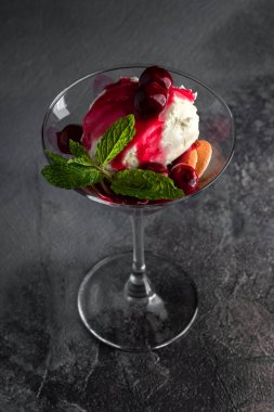Kiraz soslu tatlı, bisküvi ve martini bardağında nane şekeri gri masa ve siyah arka planda. en üstteki görünüm