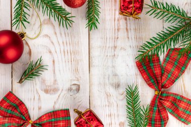 Noel kırmızı kareli yaylar ve yeşil köknar ağacı dalları ve xmas dekorasyonları yazı için çerçeve oluşturuyor, beyaz ahşap arka planda yaratıcı minimalist kompozisyon, düz uzanma, üst görünüm, kopyalama alanı
