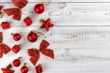 Kırmızı oyuncaklar ve kareli yay ile Noel kompozisyonu, beyaz ahşap arka planda yeni yıl tatili konsepti, düz yatış, üst manzara, kopyalama alanı