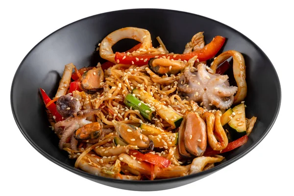 Grilled octopus baby, mussels, squid rings and vegetables mix, noodles in sauce, red pepper, sesame seeds in a black plate isolated on white background, side view — Stock Photo, Image