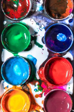 Okul konseptine geri dönersek, suluboya resimler çizmek için dağınık palet yakın plan, üst görüş, parlak renkli soyut hobiler ve yaratıcılık, çocuk için eğitim sanatı