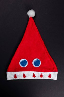 Karanlık Noel düz kompozisyonu, Noel Baba kırmızı şapkalı, kürklü, Noel ağaçlı ve kocaman gözlü, yeni yıl minimalist tebrik kartı konsepti.