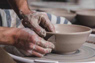 Potter, stüdyodaki çömlekçi çemberinde bir kase beyaz kil yapıyor. Yaratıcılık ve sanat kavramı, yatay fotoğraf.