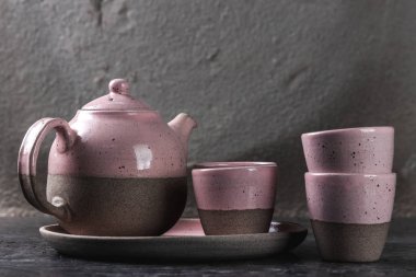 Gri arka planda el yapımı çaydanlık ve fincanlar, fotokopi alanı ile sanat eseri konsepti, iç dekoratif seramiğin pembe rengi.